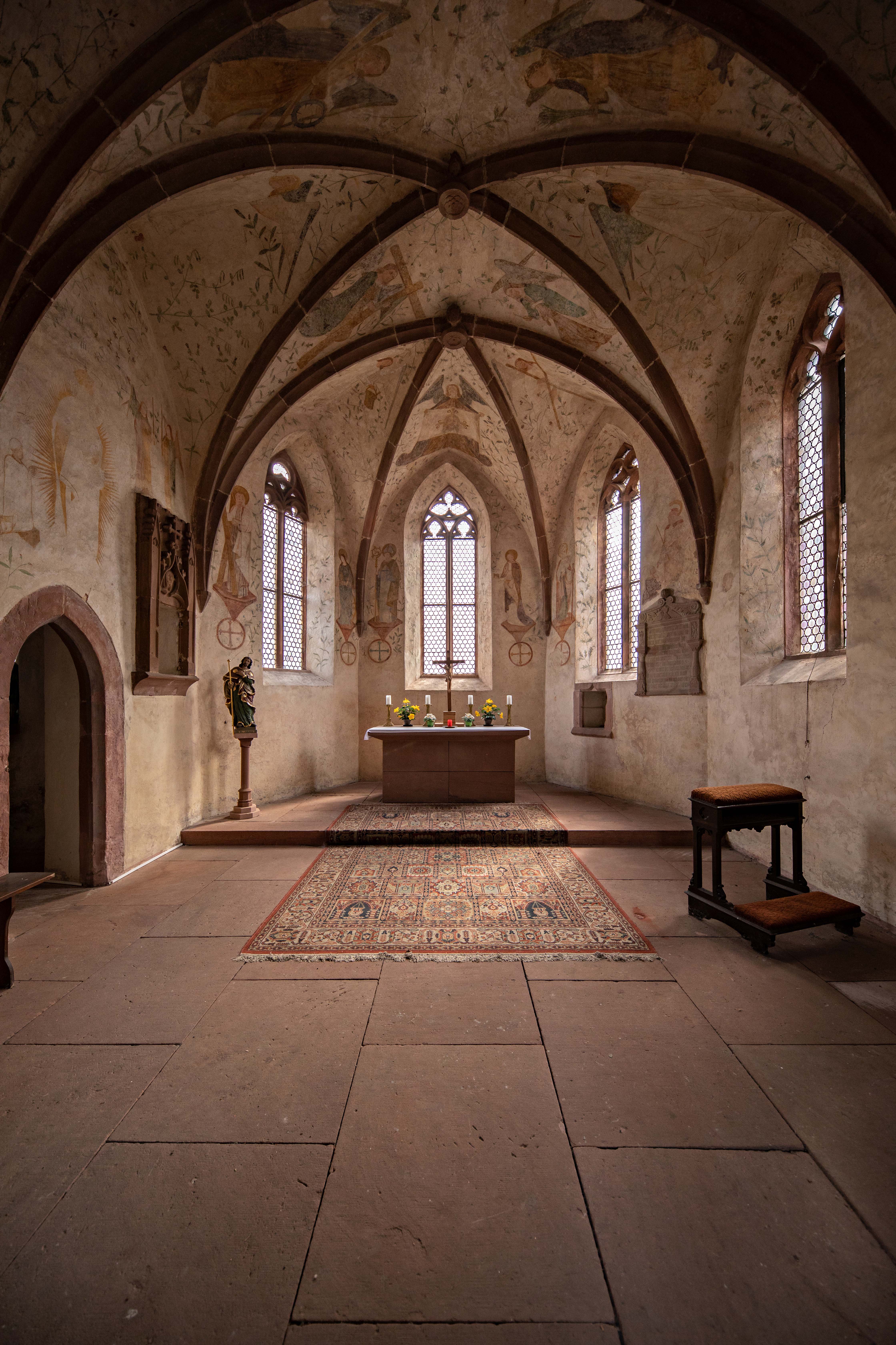 Innenraum der Alten Kapelle in Landstuhl. Blick in Richtung des Chors. Die Decke schmücken Kreuzrippengewölbe und Malereien