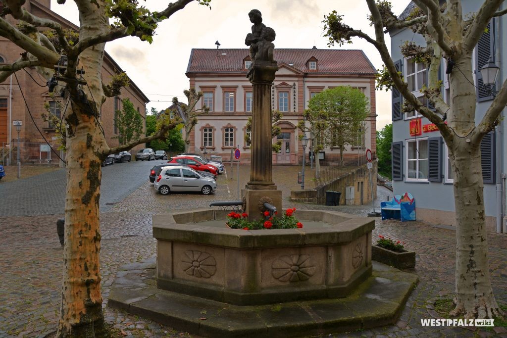 Hutmacherbrunnen am Marktplatz in Kusel. Im Hintergrund ist das Rathaus zu sehen