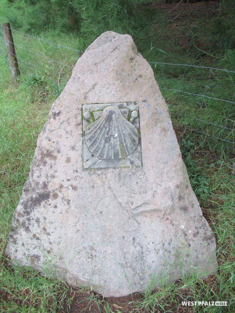 Fels mit dem Muschel-Symbol des Jakobpilgerwegs