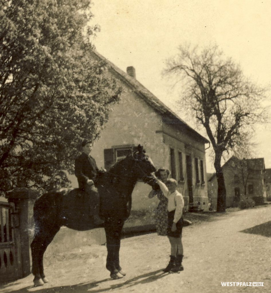 Familie vor dem Wohnhaus mit Schmiede in der Hauptstraße 49 in Hinzweiler.