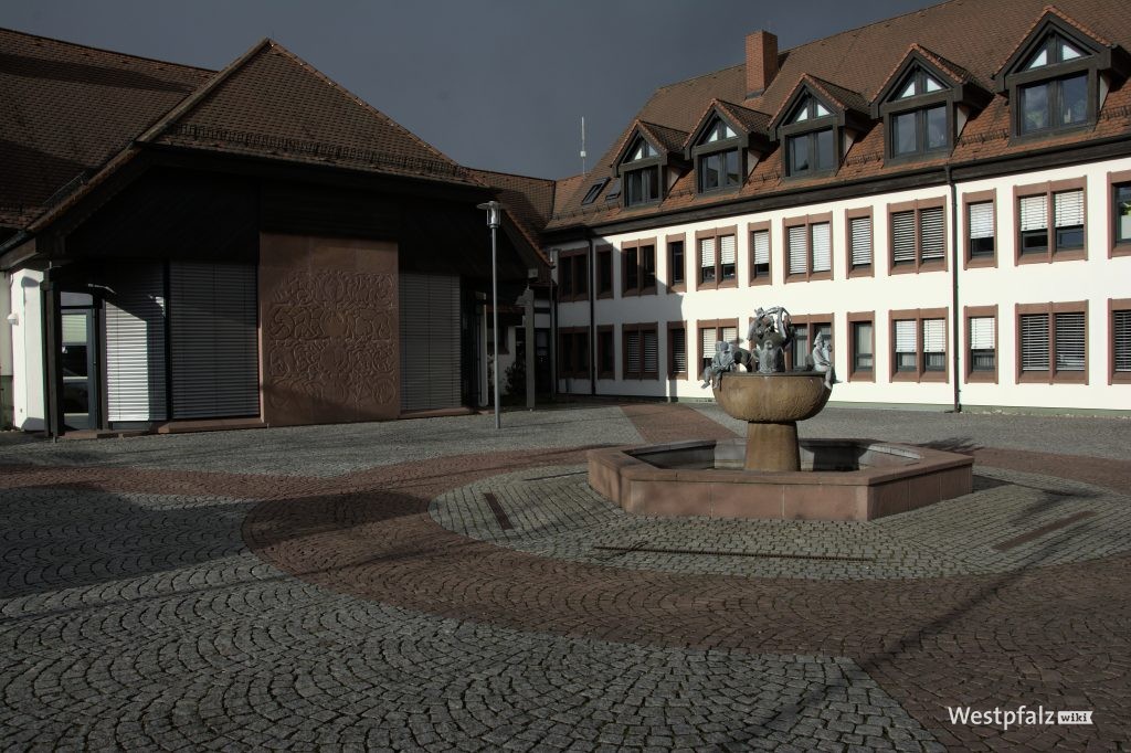 Brunnen auf dem Zentrum des Platzes, Verwaltungsgebäude im Hintergrund