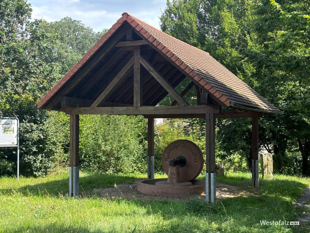 Mühlenstein der ehemaligen Obstmühle oberhalb des Brunnens
